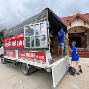 2 công nhân Nhà sạch Hạ Long 24h đang vận chuyển đồ đạc nội thất từ thùng xe tải vào nhà cẩn thận.