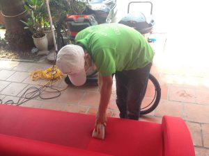 Nhân viên đang sử dụng máy phun hút hơi nước nóng để giặt ghế sofa văn phòng bị bụi bẩn.