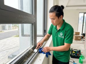 Công nhân đang vệ sinh cạo sơn bả trên cửa kính trong gói dọn tổng vệ sinh nhà mới xây Hạ Long.