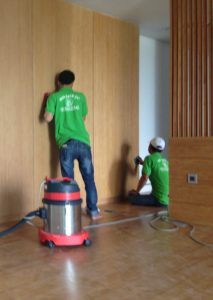 Đội 3 công nhân vệ sinh đang sử dụng máy hút bụi công nghiệp làm sạch sàn nhà.