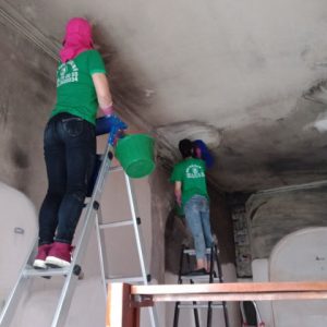 Hai công nhân Nhà sạch Hạ Long 24h đang xử lý và làm sạch các vết mốc đen trên tường nhà.
