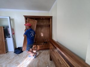 Thợ mộc Nhà Sạch Hạ Long 24h đang sử dụng máy khoan pin để tháo bản lề tủ quần áo gỗ công nghiệp.